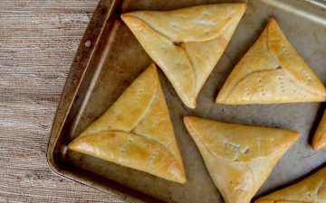 The image is a triangle shaped pine tart on a baking sheet