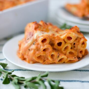 close up of the baked-ziti in a white plate with a green garnish