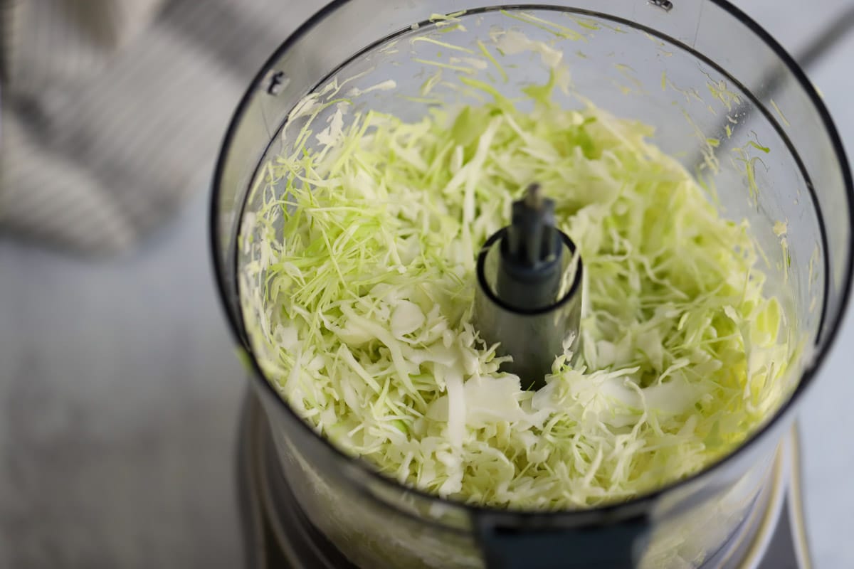 Shredded cabbage inside food processor bowl.