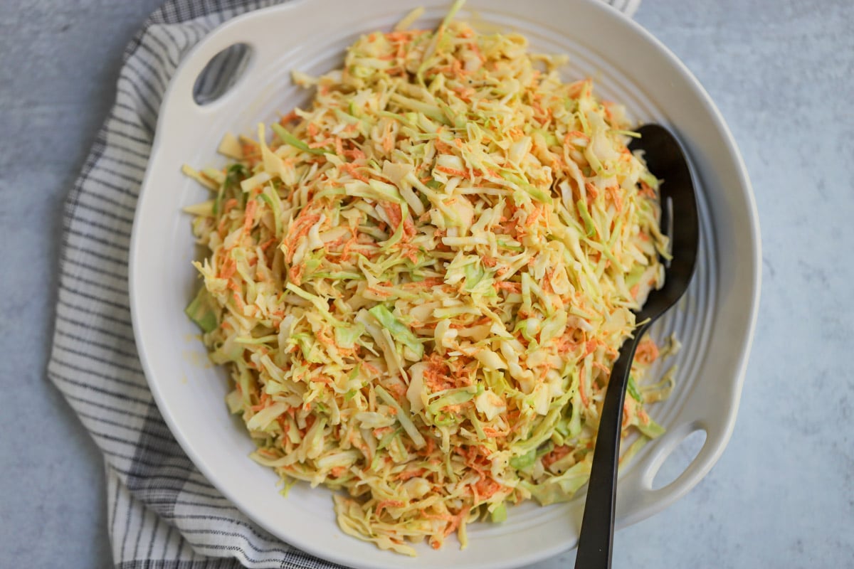 Coleslaw plated in white serving dish.