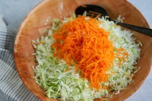 Mixing bowl with shredded cabbage and carrots no coleslaw dressing.