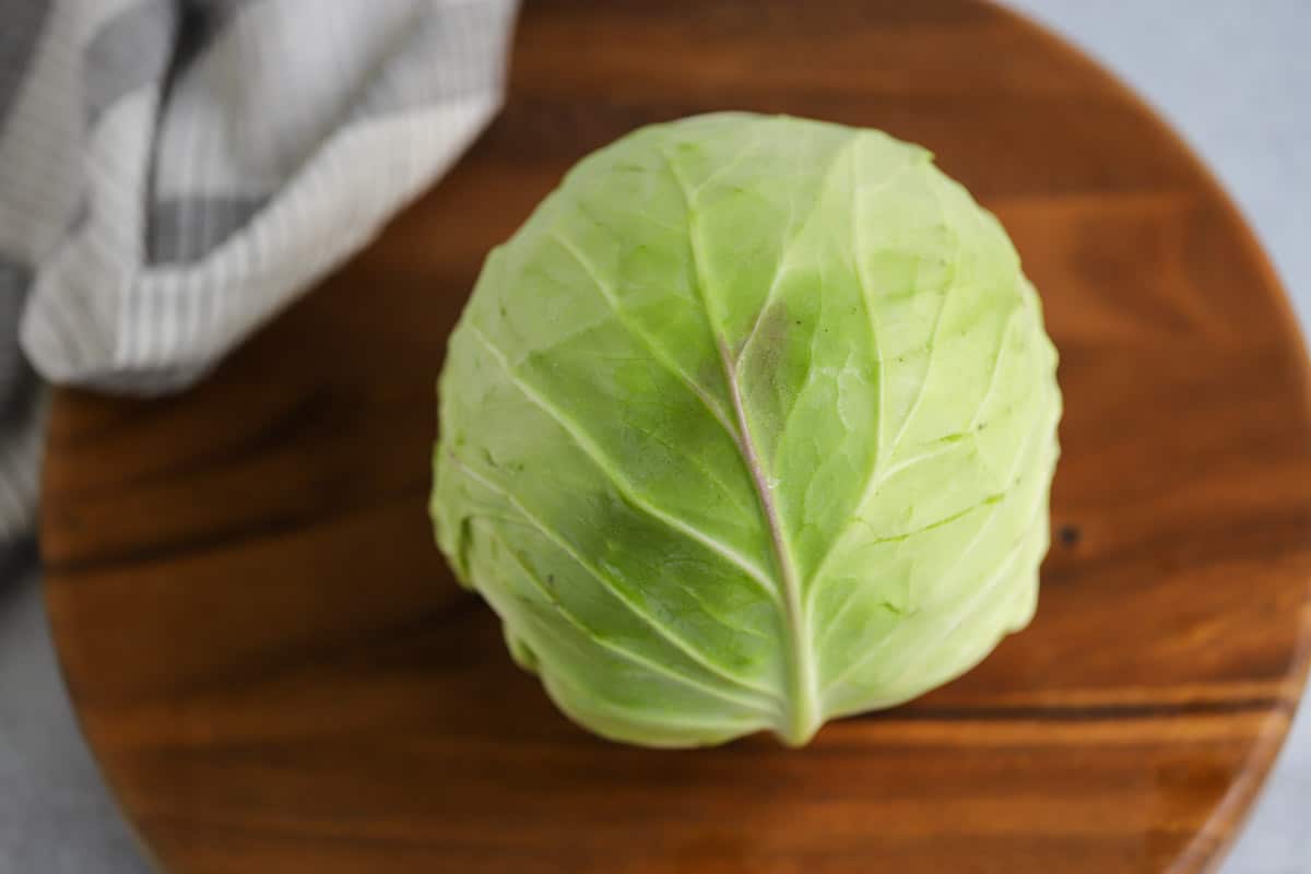 Whole head of cabbage on cutting board.