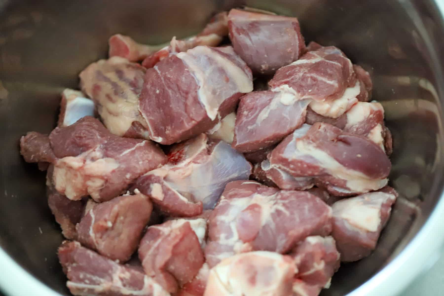 Chunks of lamb leg in mixing bowl.