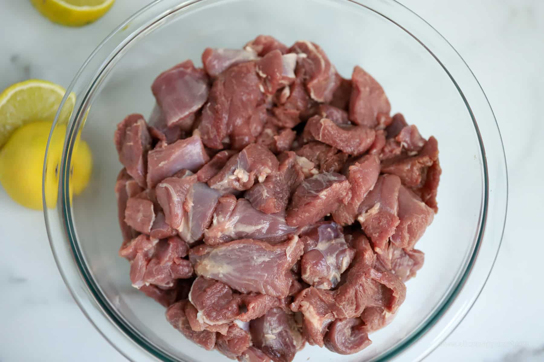 Raw lamb chunks in mixing bowl.