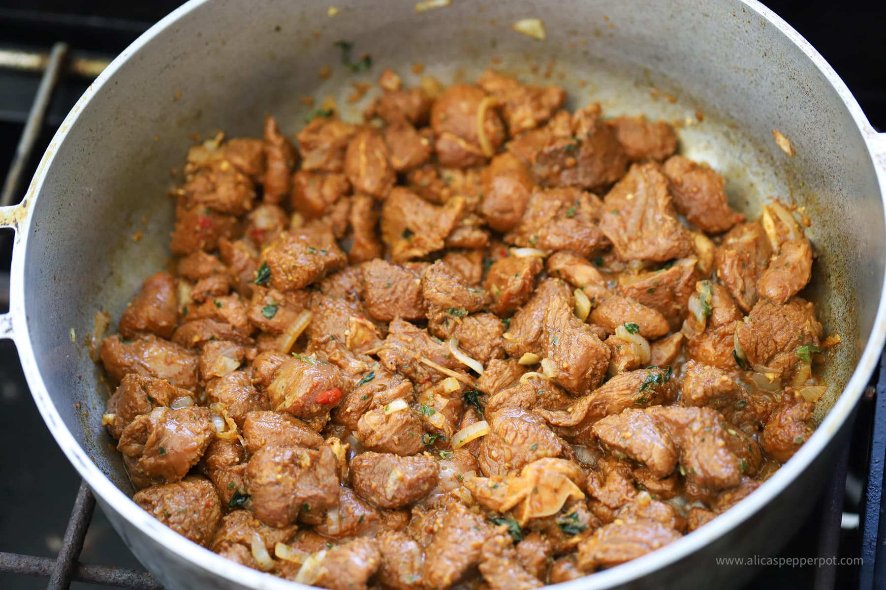 Sautéing casareep lamb in wide pot.