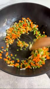 Image of stir frying bora and carrots in black wok.