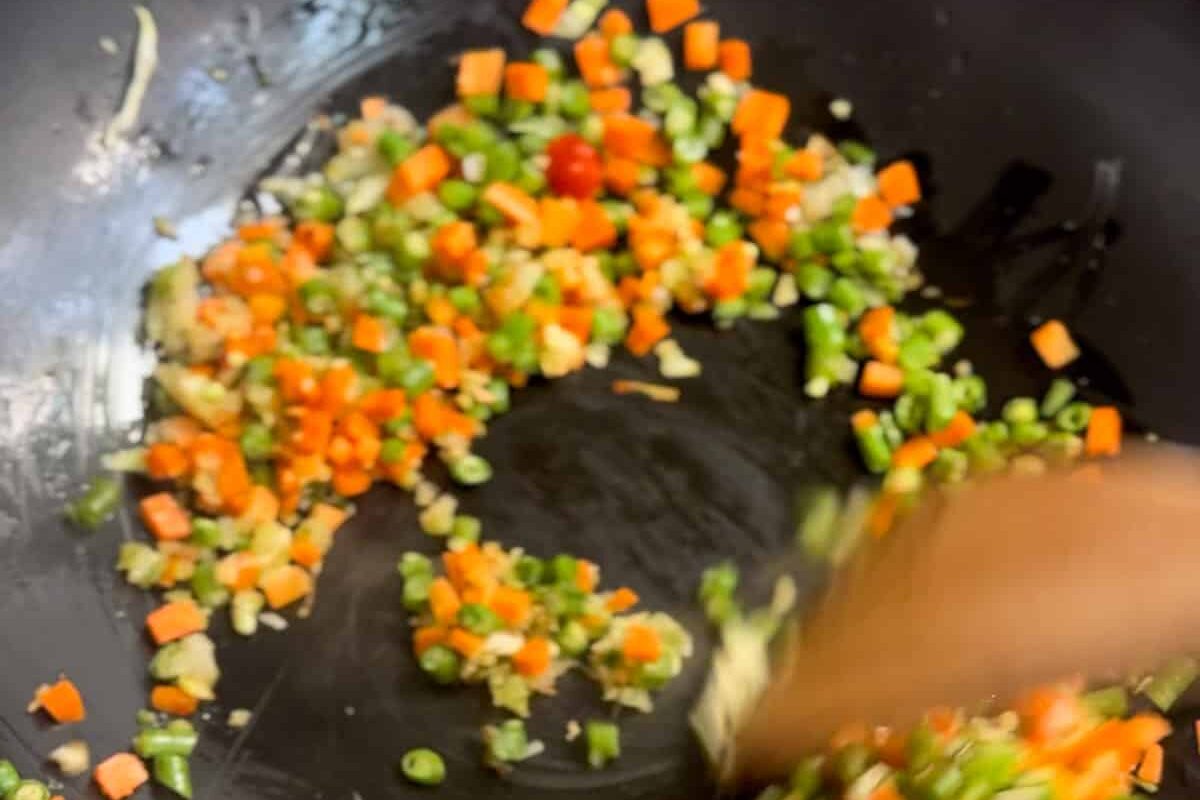 Image of stir frying bora and carrots in black wok.