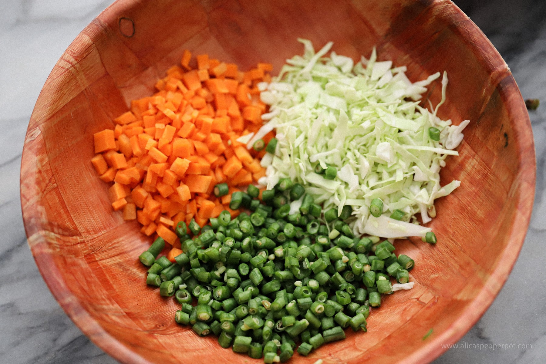 Image of bamboo bowl with cut up carrots, bora, and cabbage inside.