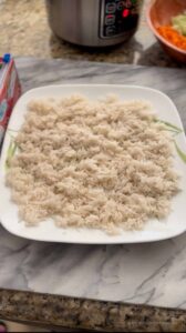 Image of cooked white jasmine rice in a plate spread out to cool off.