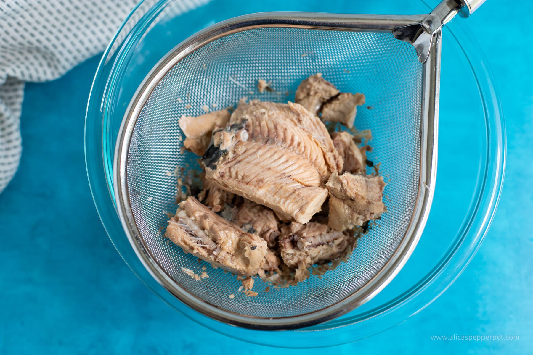 Canned salmon draining in mesh strainer.