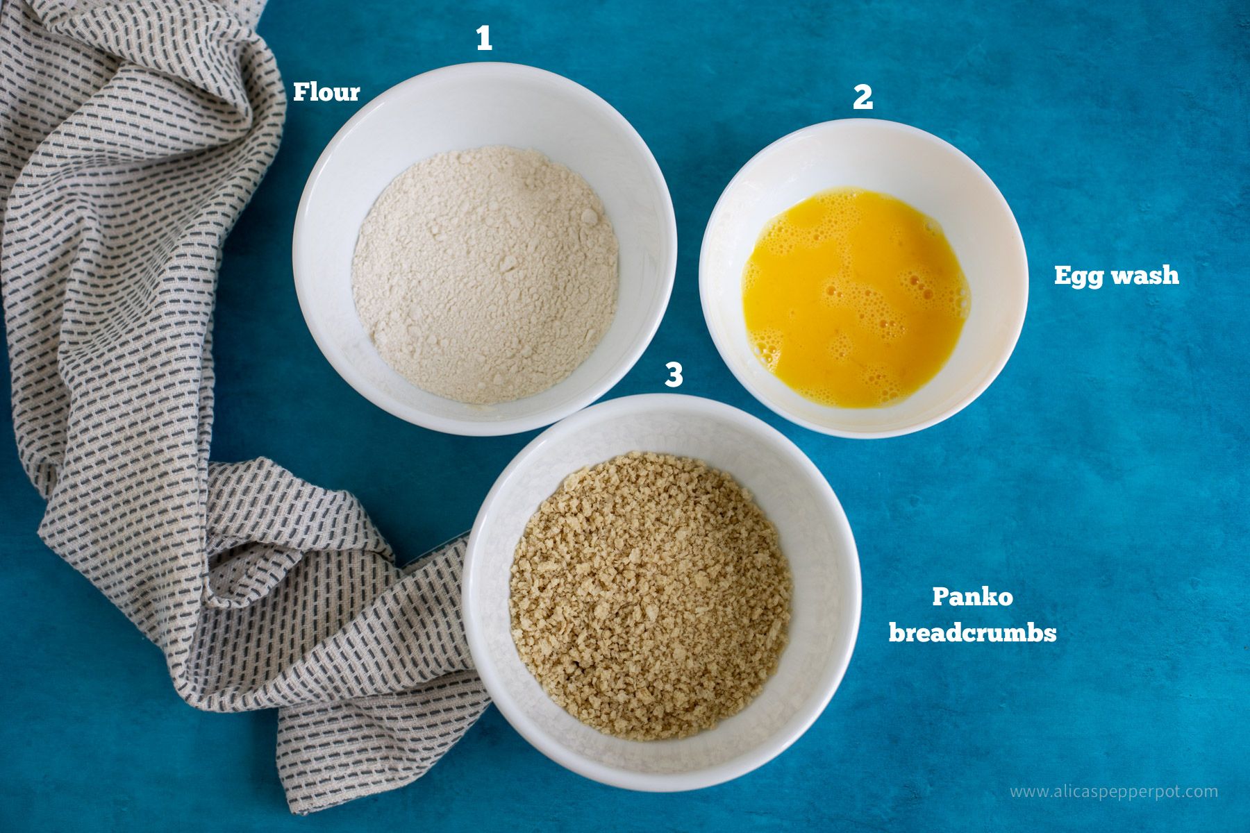 This is an image of salmon cake breading with 3 bowls. One has flour, the second has egg wash, and the third has panko breadcrumbs.