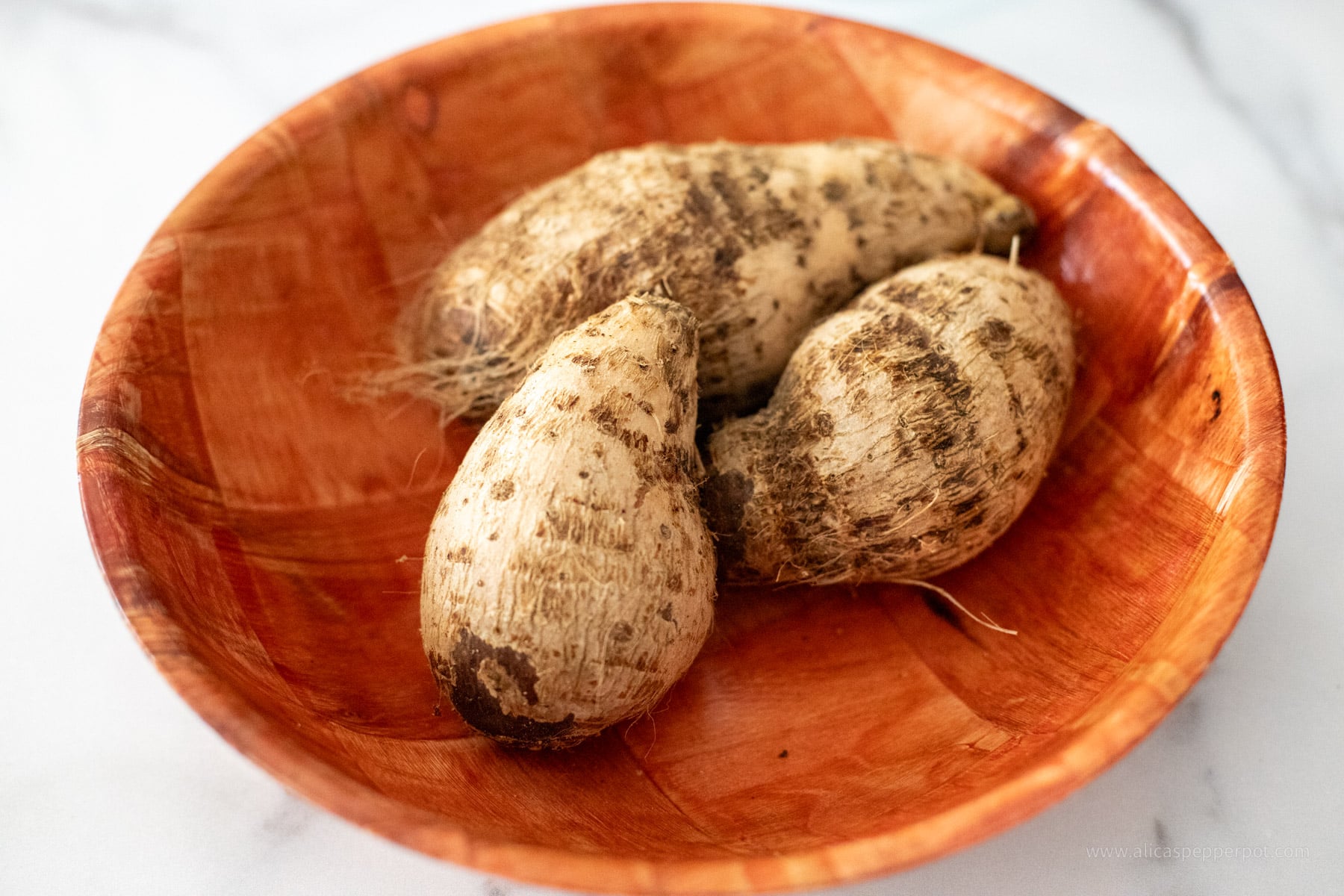 3 whole Eddoe/taro root vegetable in a bamboo bowl.